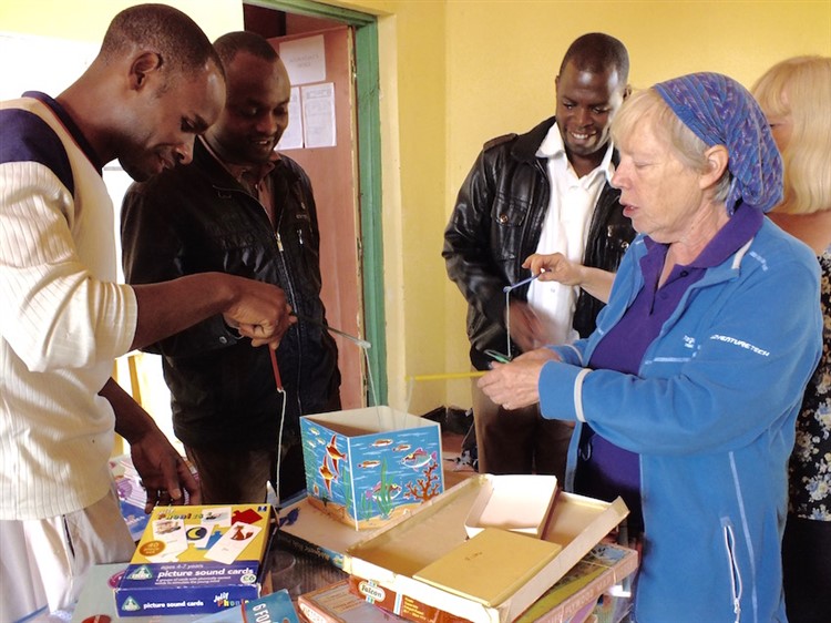 Grace and Isobel demonstrate teaching aids to staff at King Solomon Academy, Byumba
